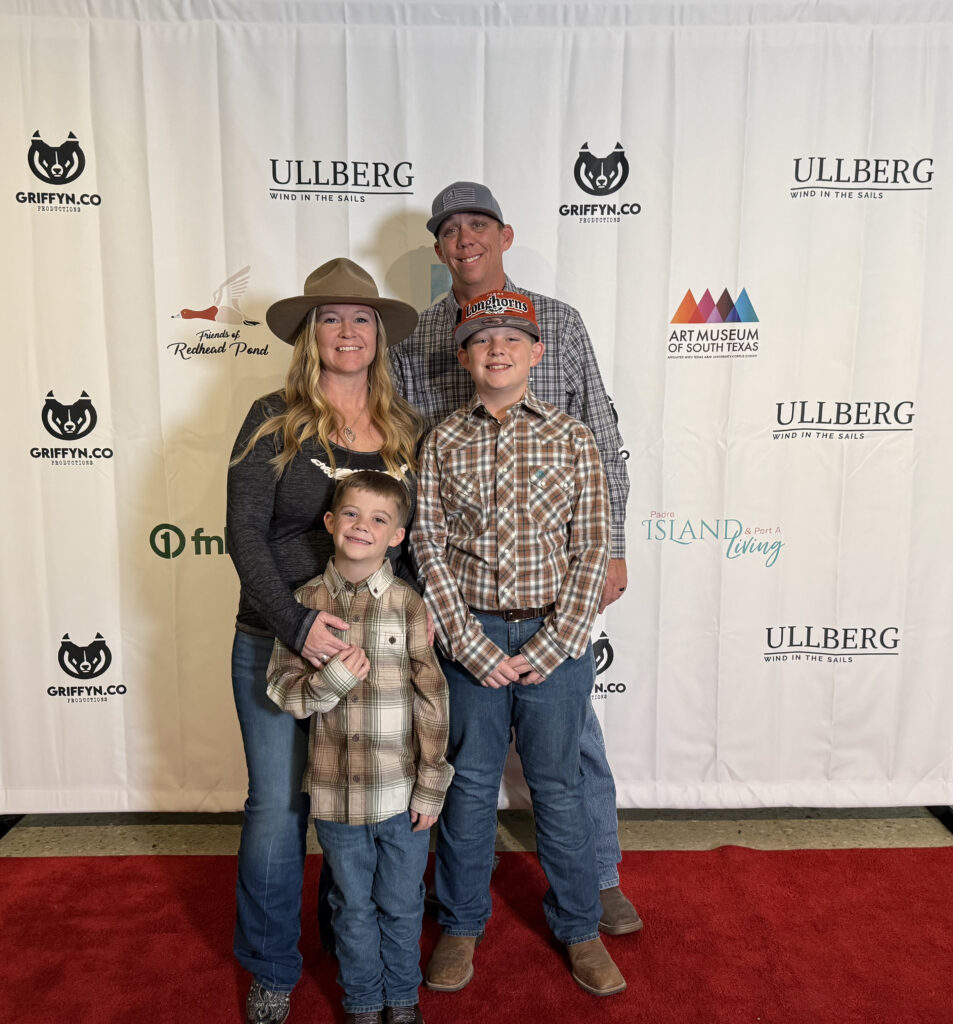 Family poses on red carpet event backdrop.