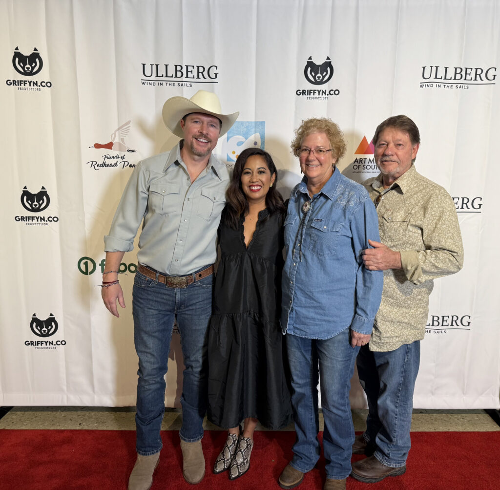 Four people posing on a red carpet event.