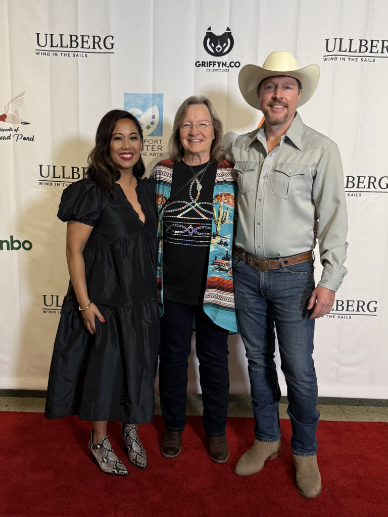 Three people standing on red carpet event.
