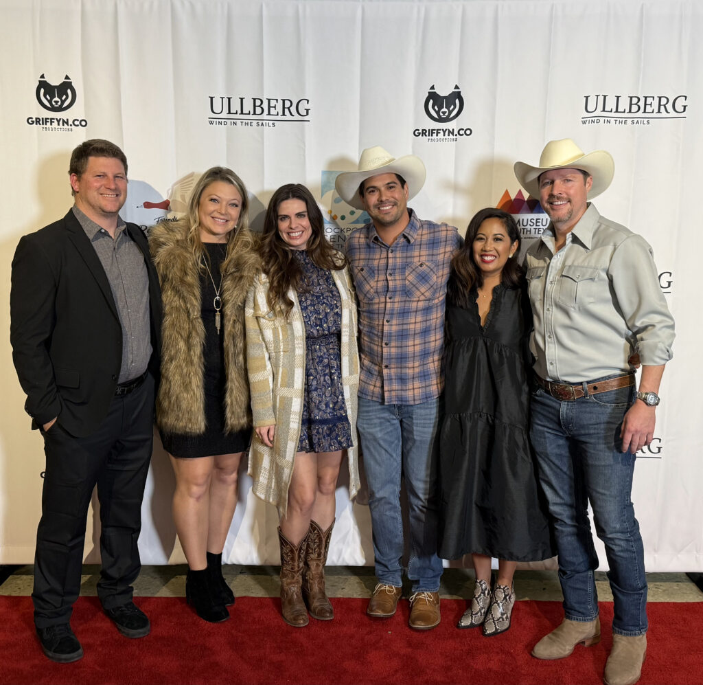 Group of people smiling on red carpet event.