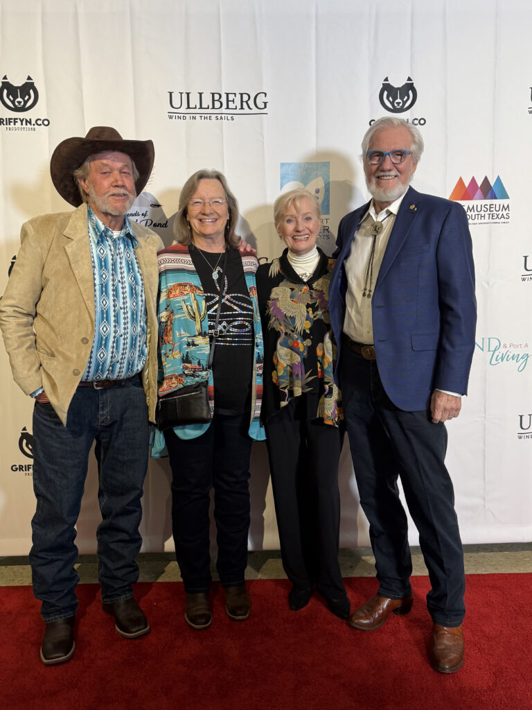 Four people posing on red carpet event.