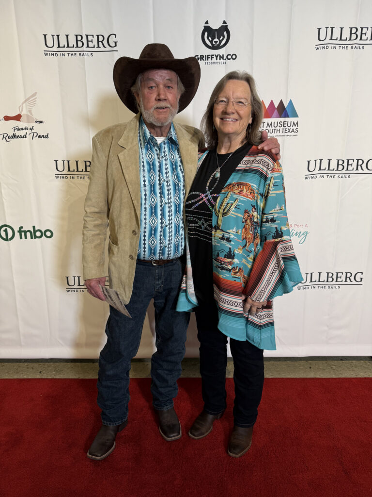 Couple smiling on red carpet at event.