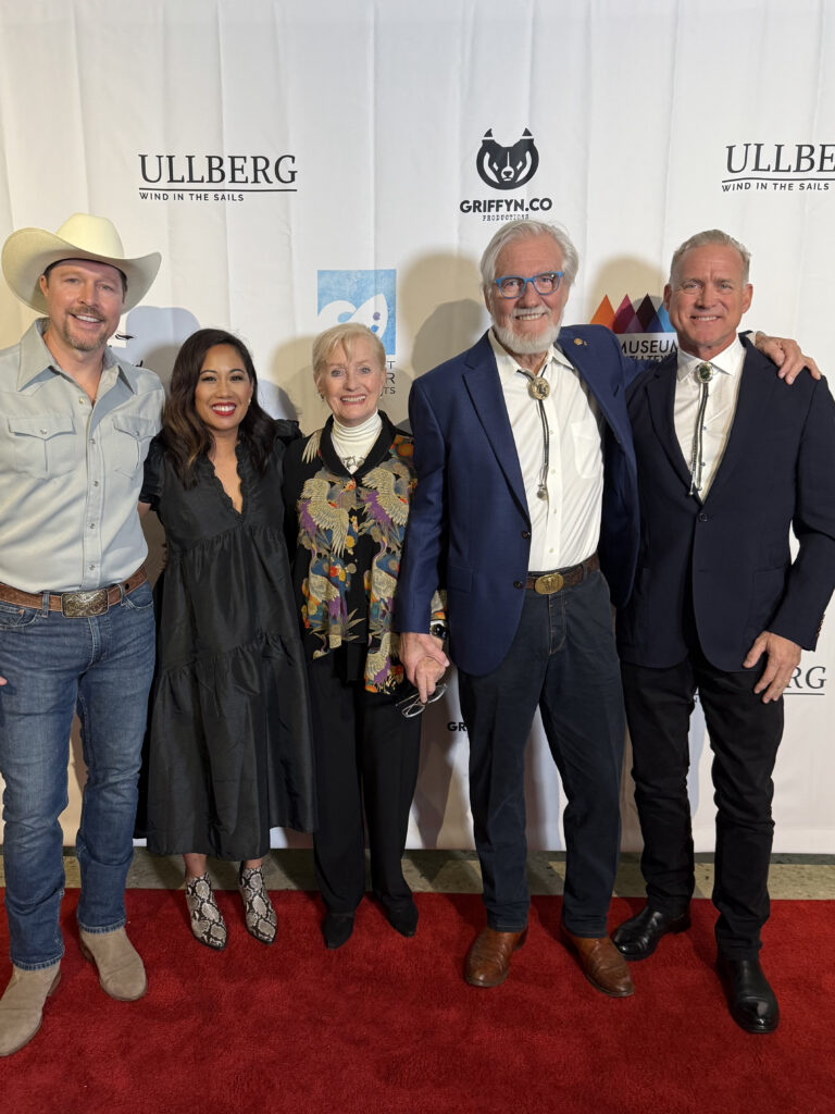 Group posing on red carpet event backdrop.