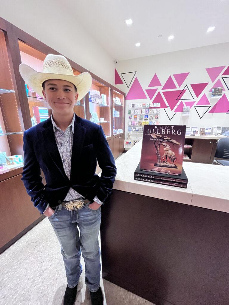 Young person in cowboy hat by a book display.